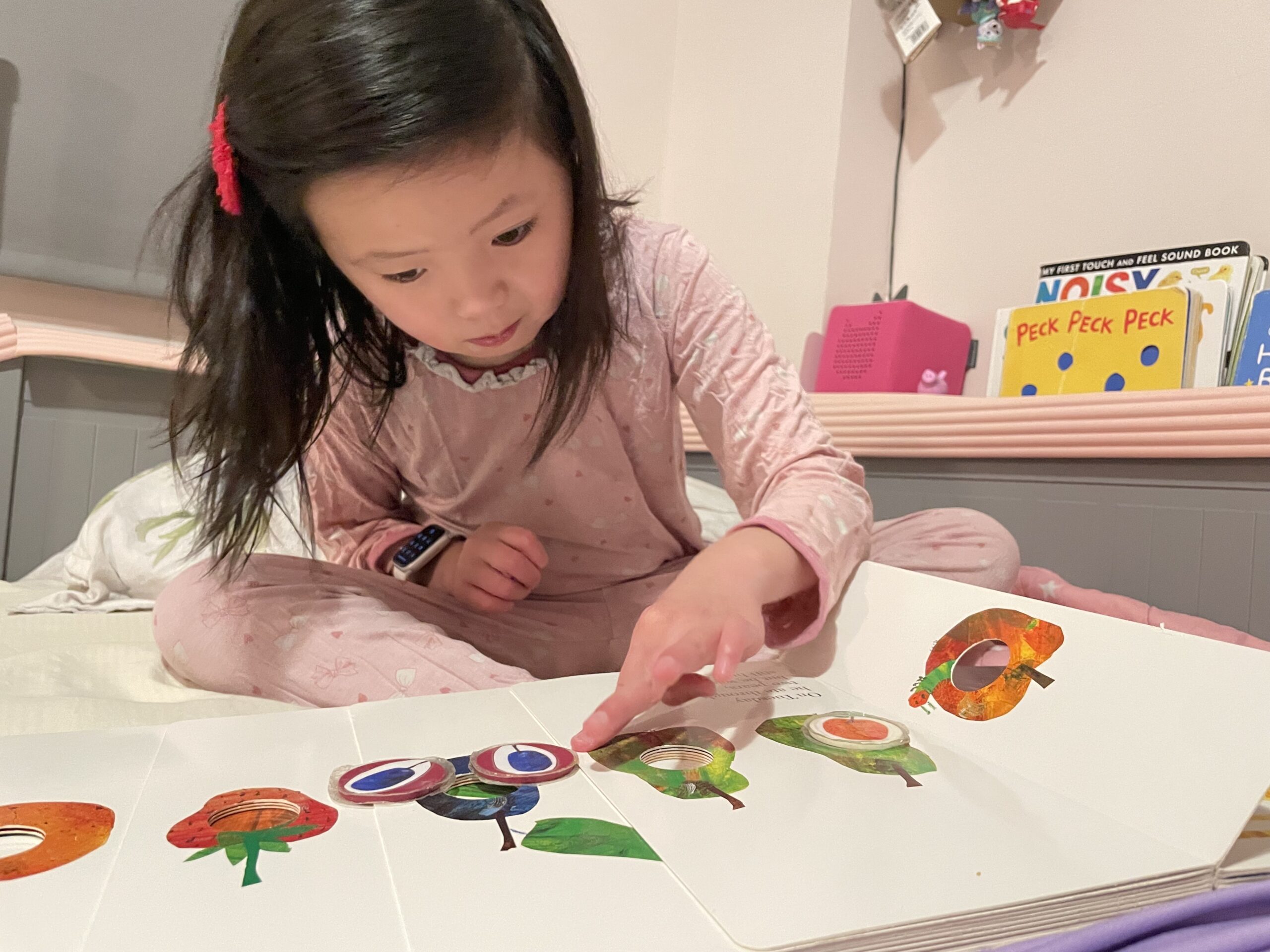 Larissa W reading hungry caterpillar Larissa is on her bed reading The Hungry Caterpillar.