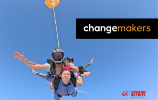 A woman and skydiving instructor falling through a bright blue sky.