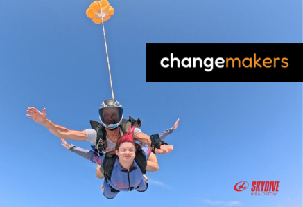 A woman and skydiving instructor falling through a bright blue sky.