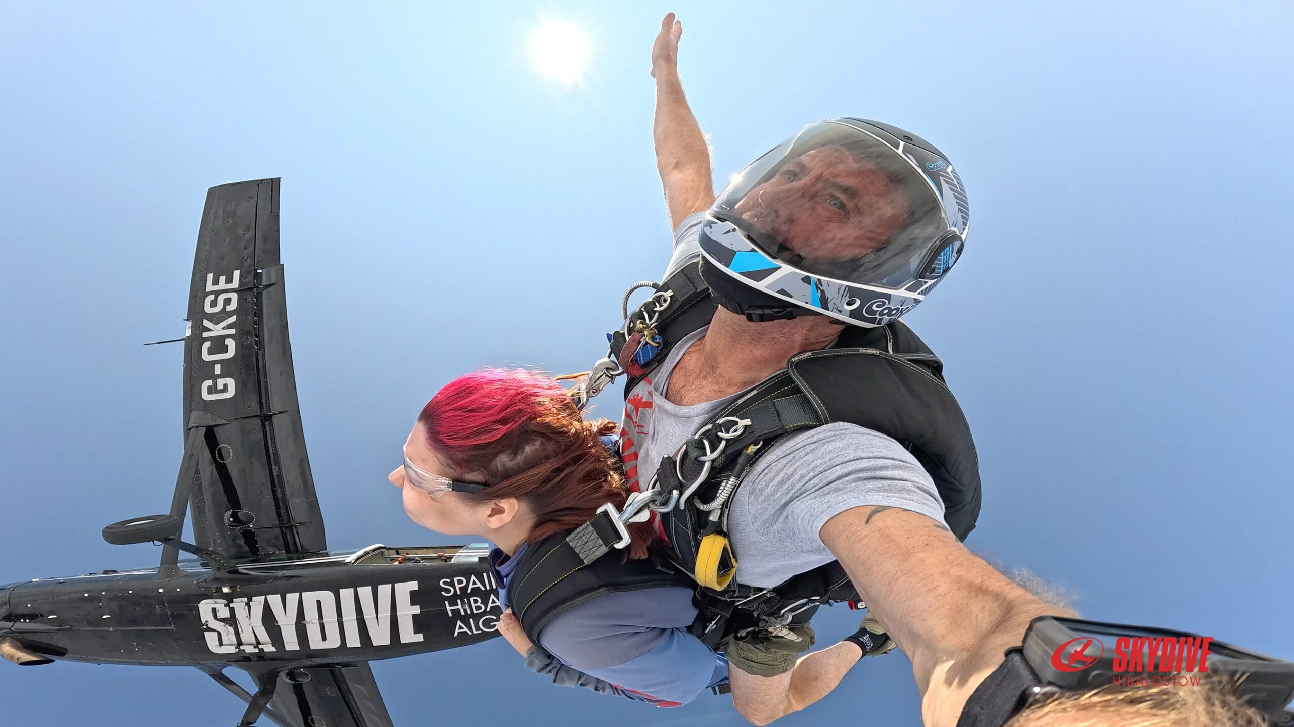 Millie and a skydiving instructor jumping from a grey plane thousands of feet in the air.